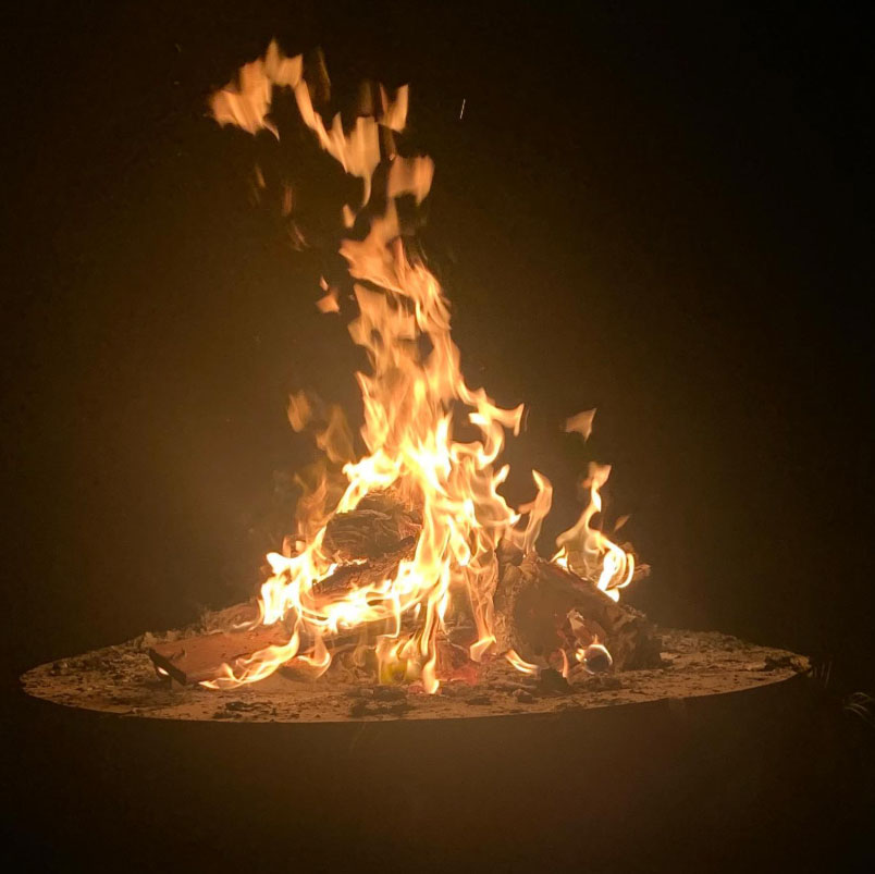 Backyard campfire pit burning at night under a dark rural Illinois sky